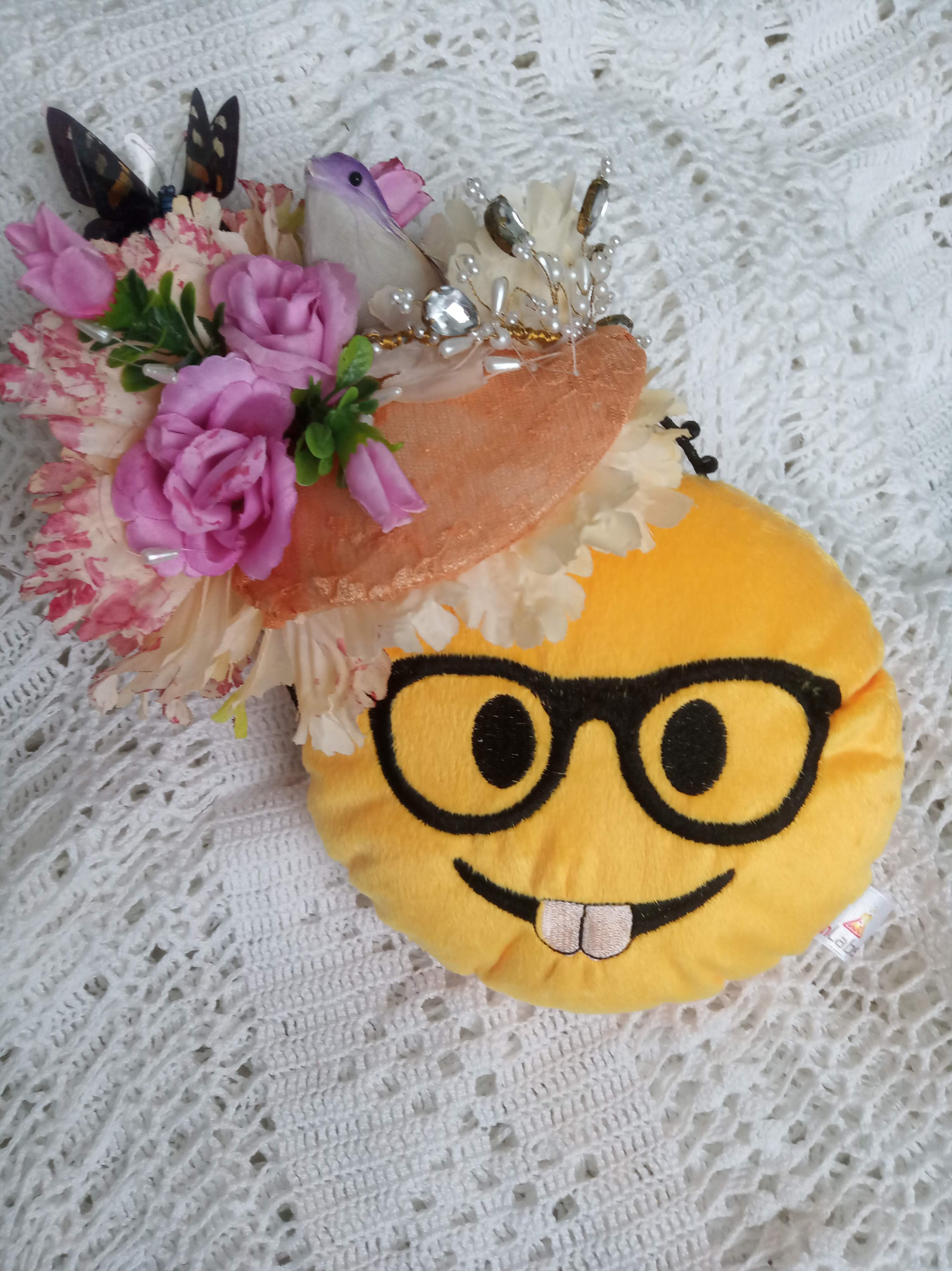 Foto do avatar da Carole nas redes sociais: um emoji amarelo de óculos com flores e pássaro na cabeça